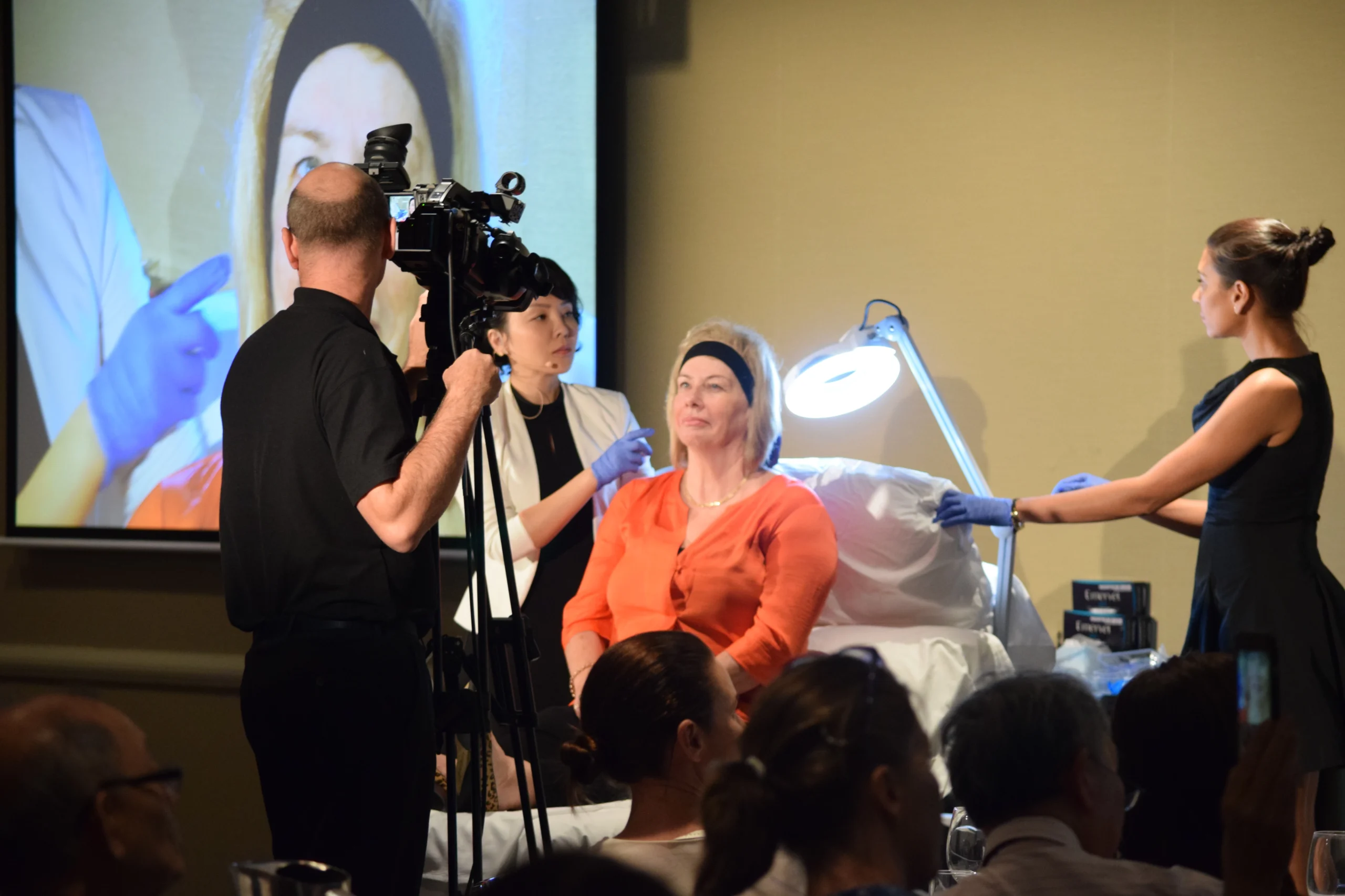 Dr Suzanna Luo explaining a live demonstration while a camera relays detail to a large screen